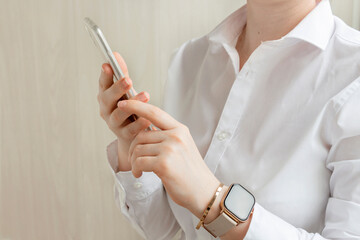 Young business woman wear casual white shirt and smartwatch holding smartphone in hands. Stay focused concept.