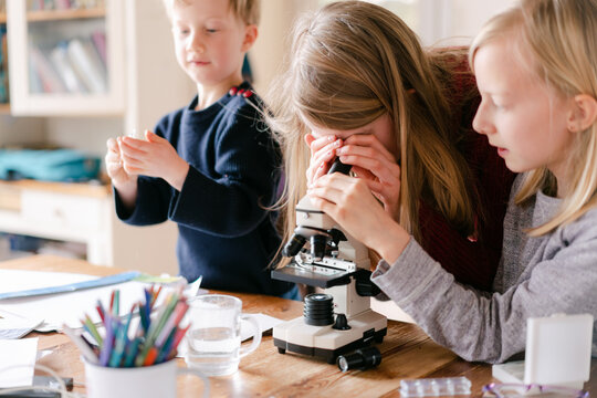 three kids  looking through microscope 