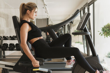 Fototapeta na wymiar Athletic woman exercising on a stationary bike in the gym