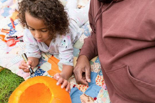 Girl carves pumpkin with thin blade