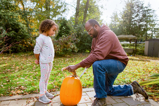 Dad carves pumpkin with child