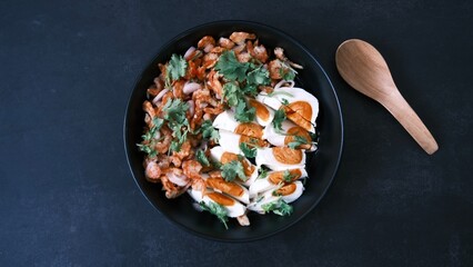Salt egg spicy salad with dried shrimps on black background, Thai food breakfast.
