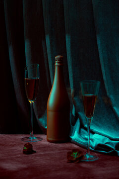 Red wine glass and shadow of bottle. Container for alcoholic beverages. Colorful lighting indoors.