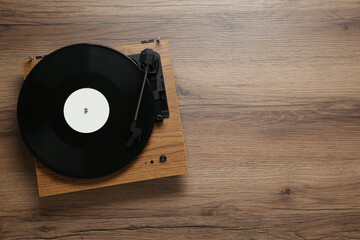 Turntable with vinyl record on wooden background, top view. Space for text