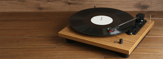Turntable with vinyl record on wooden background. Space for text