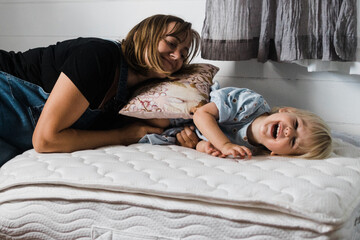 pregnant mother and daughter play on mattress
