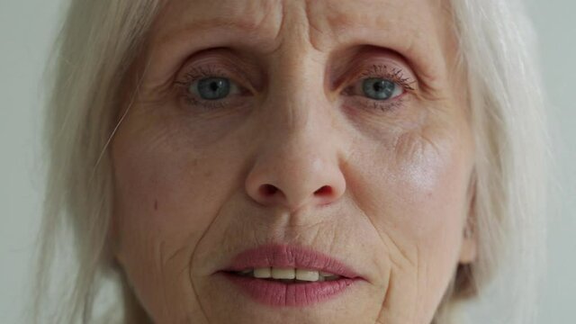 Close-up of the face of an elderly woman with gray hair, looking at the camera