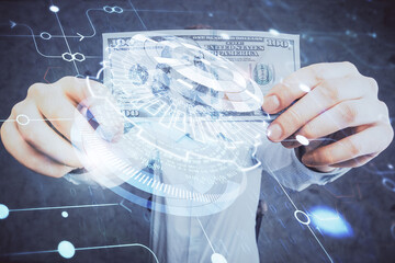 Double exposure of technology drawing hologram and us dollars bills and man hands. Data concept