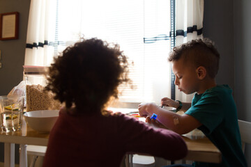 Boy eats breakfast with sister at table