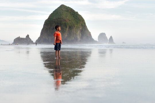 Black boy on beach framed by Haystack Rock