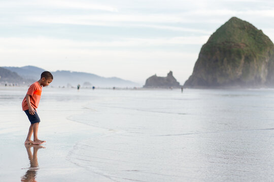 Black boy dodges waves by by Haystack Rock