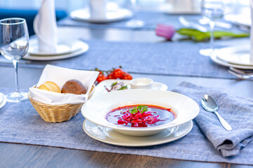 Beetroot soup, borscht, beautifully served in a white plate on the table in the restaurant. National Russian, Ukrainian cuisine. Restaurant menu