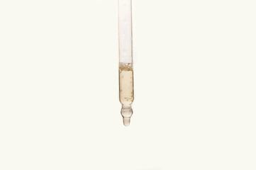 Pipette with essential oil on blurred flower background