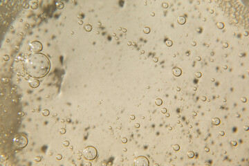 Cosmetic texture with bubbles on beige background. Cleanser, shampoo, wash - liquid soap, shower...