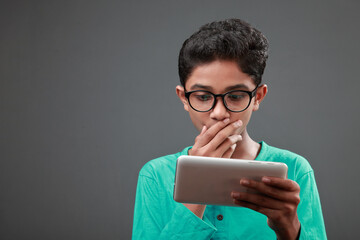 Young boy with surprised face looking at a digital tablet
