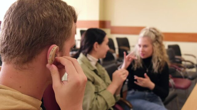 Three hard of hearing and deaf students communicate in sign language in a university classroom.