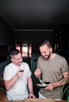 Gay Couple Dining On A Salad And Drinking Wine In The Home