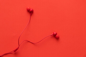 Red headphones with rolled wire, on a red background