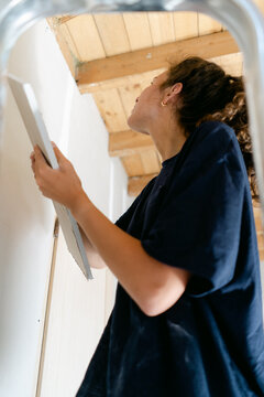 young woman putting dry wall up 