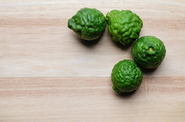Many of the kaffir lime fruits are green and fresh, placed on softwood material with beautiful patterns.