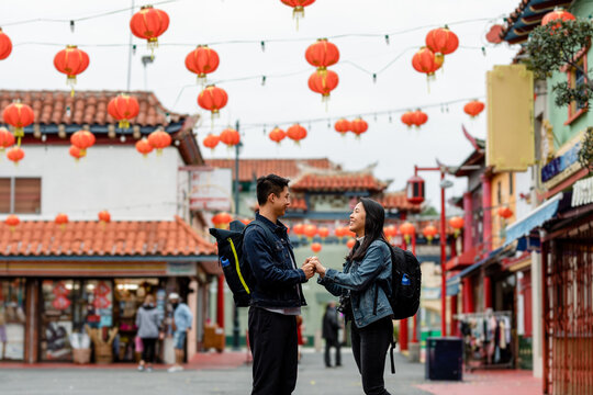 Happy Asian Couple Hold Hands Under Red Lanterns in Chinatown