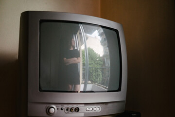Reflection of a window and a young woman in a old tv