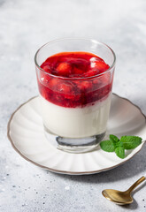 Vegan coconut panna cotta with strawberries in glass on gray background. Traditional Italian dessert. vertical image