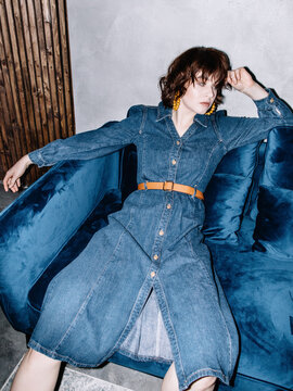 Tired woman in denim dress resting on sofa