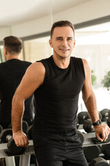 Fototapeta na wymiar Young athletic man in a free weight zone of the modern gym