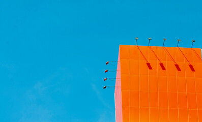 corner of orange building on minimalist sky background, billboard