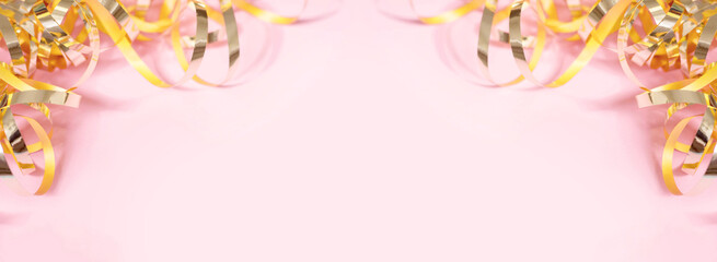 Shiny golden serpentine streamers on pink background. Banner with copy space. Top view, flat lay