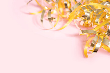 Shiny golden serpentine streamers on pink background with copy space. Top view, flat lay