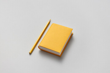 Yellow papercraft book and pencil on gray background