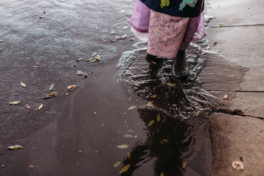 Close up image of young girl splashing in puddle
