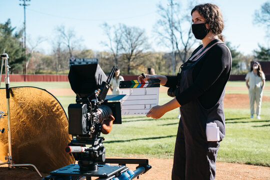 Young woman claps a clapboard in front of camera