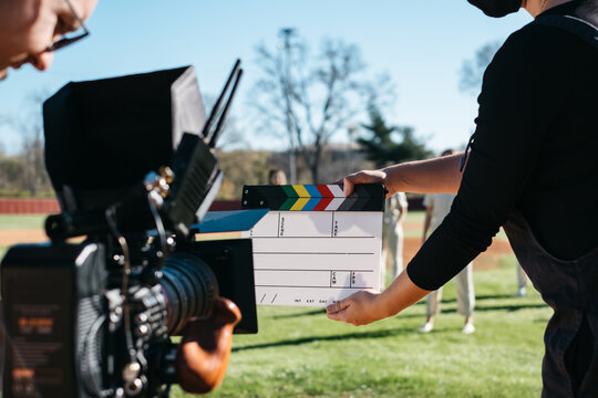Young woman holds clapboard in front of camera