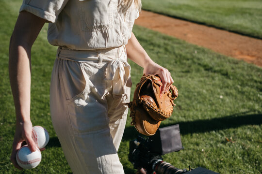 Young woman holding baseballs and glove