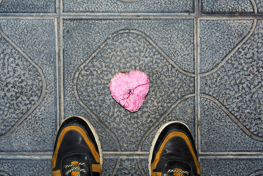 freshly trodden pink heart-shaped donut on the street