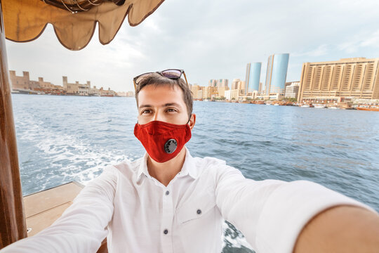 Happy man wearing medical mask traveling on the traditional boat ferry Abra Dhow on the Dubai Creek. Coronavirus and covid-19 pandemic conept