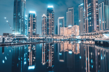 Hotels and apartment residential skyscraper buildings panoramic view in Dubai Marina Creek Harbour at night with reflections in water