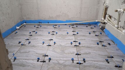 Laying the floor with ceramic tiles. Use plastic crosses to align the seams. Close-up. Installation of crosses to strengthen the tiles on the floor.