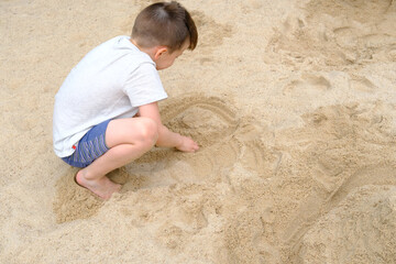 child plays in the summer with sand on the playground, in the sandbox, the concept of the development of fine motor skills, creativity, building sand castles, summer vacation, fun on the beach