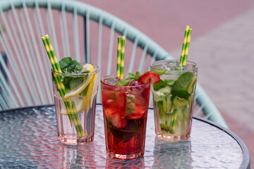 Different types of mojito cocktail on cafe background.