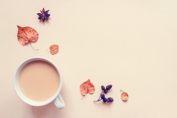 Obraz na płótnie Canvas Autumn pastel background. A cup of hot coffee or tea with milk with autumn leaves and anise. Banner with copy space for text. Flat lay, top view.