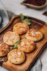 Syrniki served with sweet milk and jam on a white table.