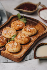 Syrniki served with sweet milk and jam on a white table.