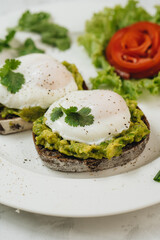 Poached eggs with avocado on sourdough toasts on white background
