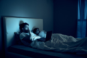 young couple at night bed with laptop leisure lifestyle technology