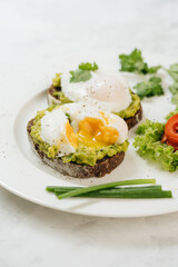 Poached eggs with avocado on sourdough toasts on white background