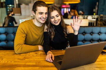 beautiful woman and handsome man hugging, using laptop and showing gestures make video call